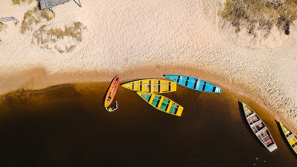 aerial photography of six wooden boats on calm body of water near seashore at daytime