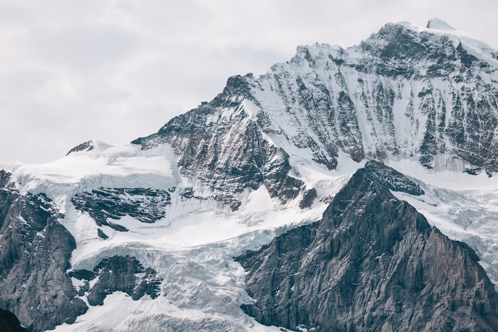 fotografia da montanha coberta de neve sob o céu nublado