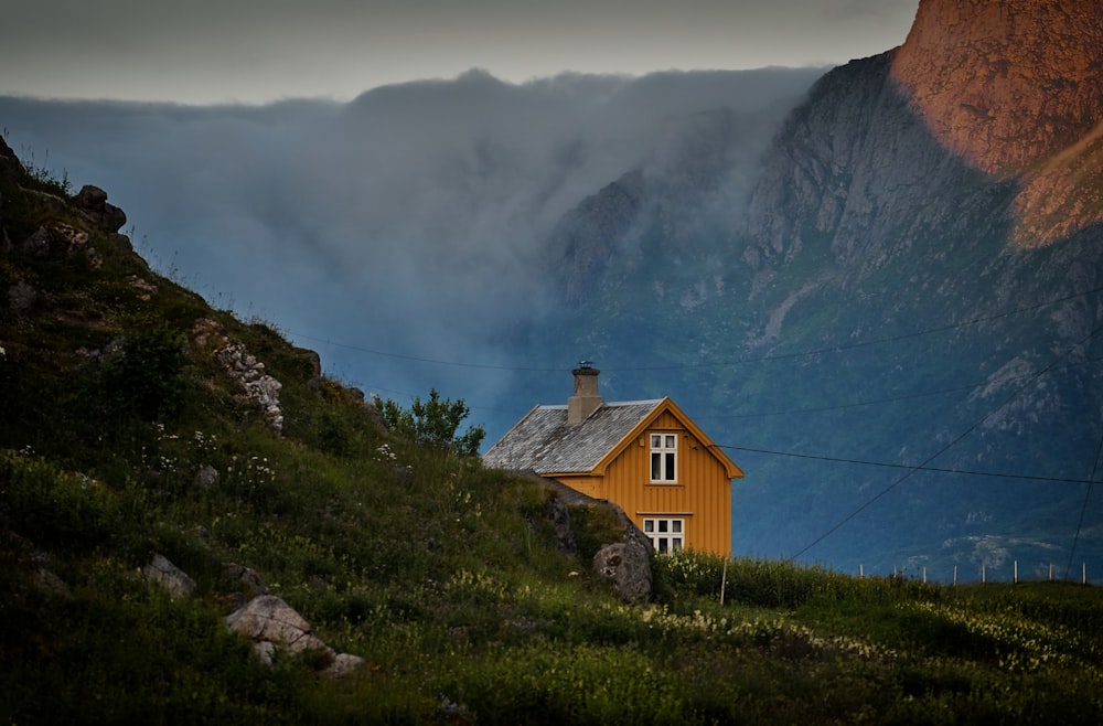 昼間の白い空の下、山の近くの茶色のコンクリートの家