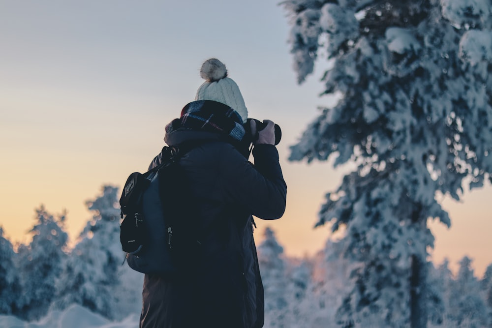 person in black winter jacket holding black DSLR camera during daytime