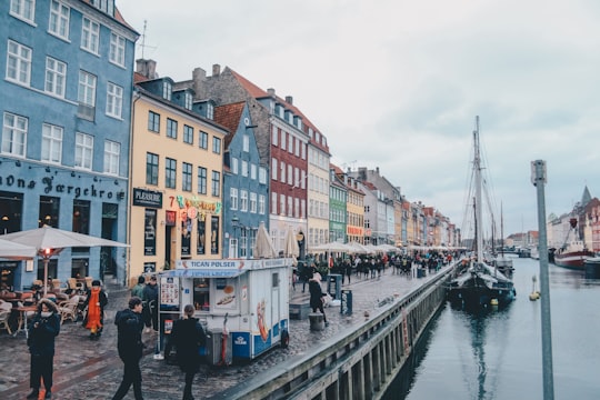 people walking in between of buildings and body of water in Mindeankeret Denmark