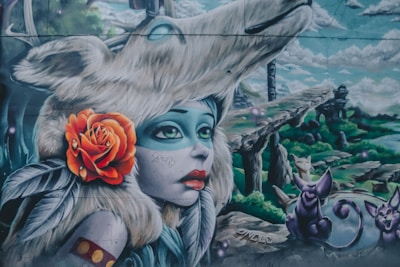 A surreal mural featuring a character with blue skin, large eyes, and red lips, adorned with a fur headdress and an orange rose. The background includes a whimsical landscape with rocky formations and fantastical creatures resembling cats.