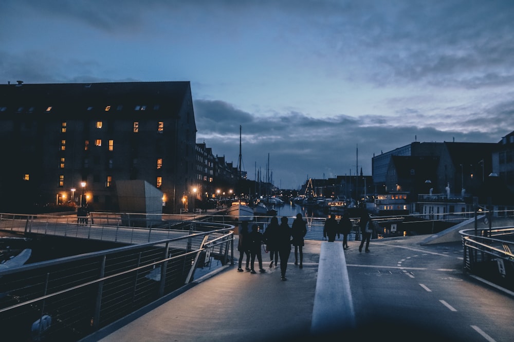 people walks on street near building under clear blue sky during nighttime