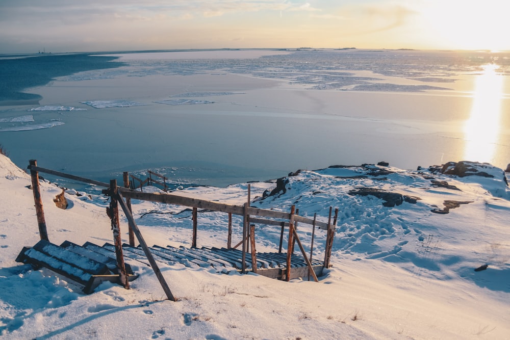 brown stairs on snow-covered mountain near body of water during daytime