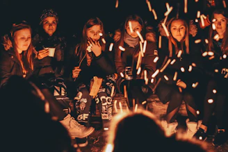 Smiling group of travelers gathered warmly around a campfire in the Andes at sunset.