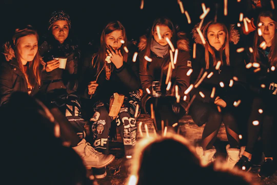 A group of diverse people smiling and sharing stories around a cozy fire.