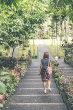 woman walking down on concrete stairs near garden plant during daytime