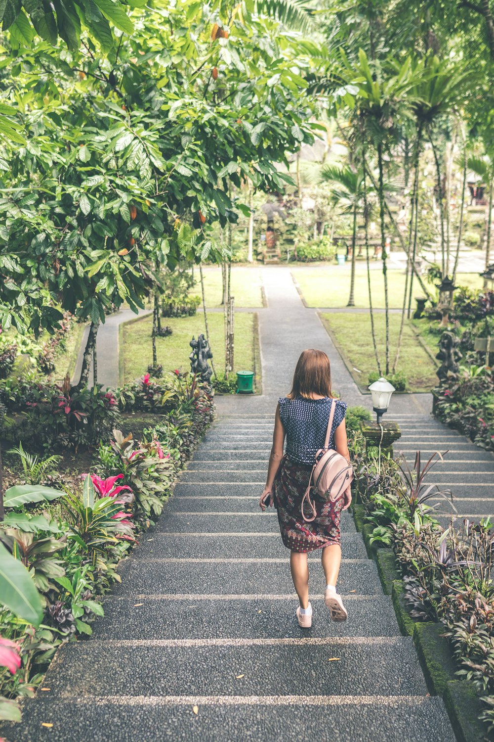 woman walking down on concrete stairs near garden plant during daytime