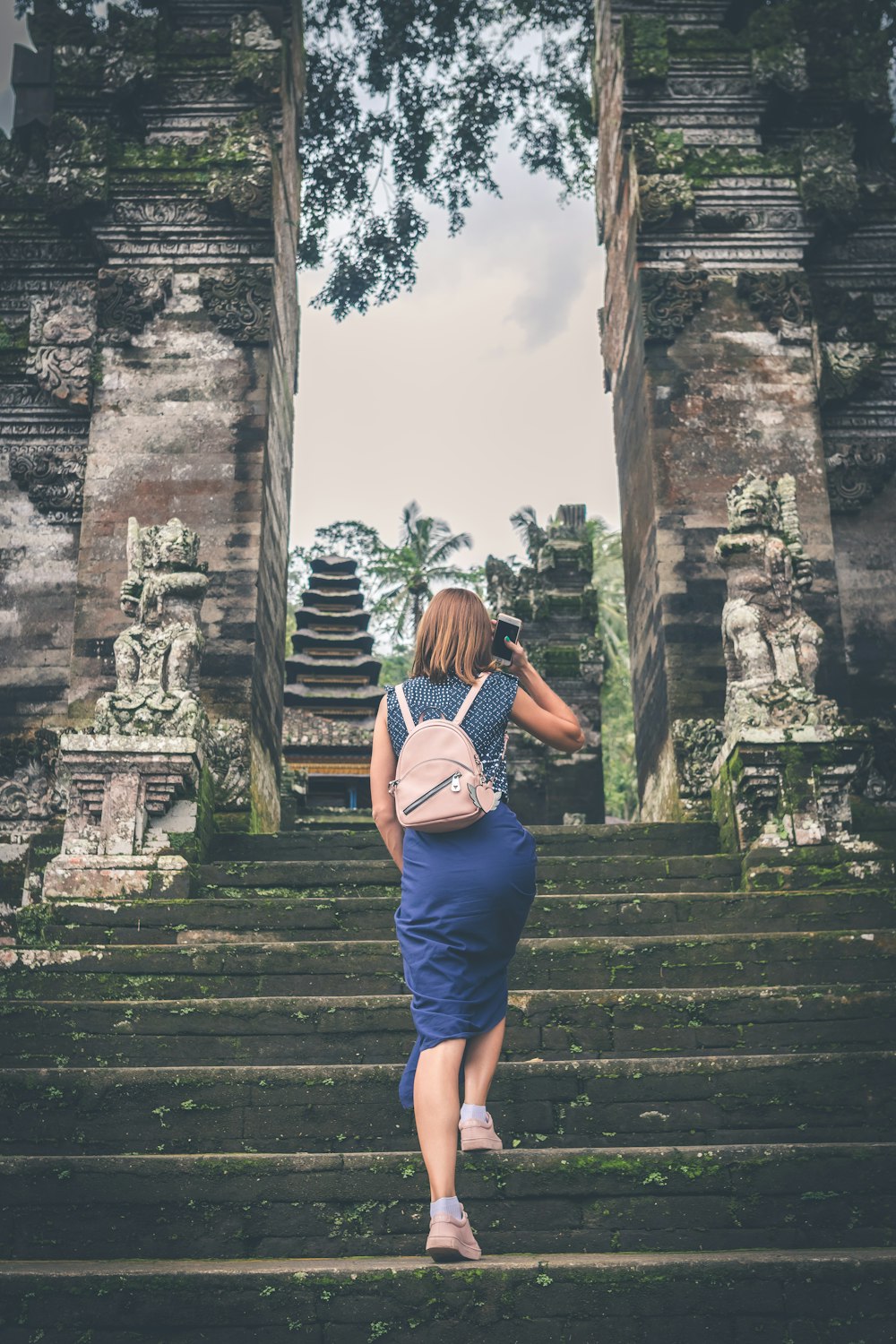 Flache Fokusfotografie einer Frau im blauen Kleid, die auf den Tempel zugeht