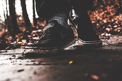 Close-up of trail running shoes on a forest path covered with leaves.