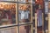 A storefront door with a glass window that has an 'OPEN' sign hanging on it. The door features gold-trimmed frames and ornate handles. Through the glass, a warmly lit interior is visible with hanging clothes and decorative lights.