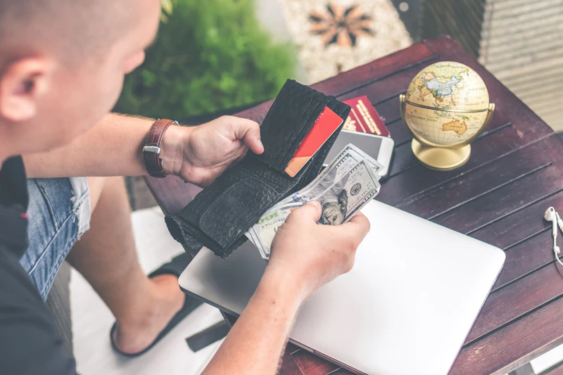 Person holding a wallet and US dollar bills