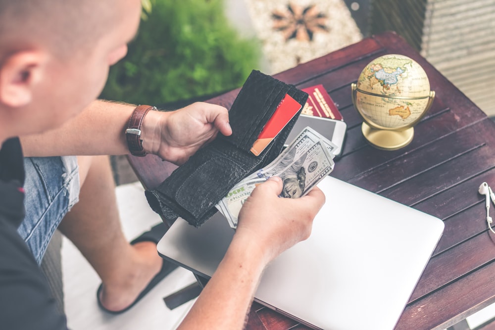 person holding wallet and US dollar bills