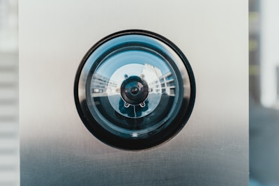 Close-up of a security camera lens with cityscape blurred in the background