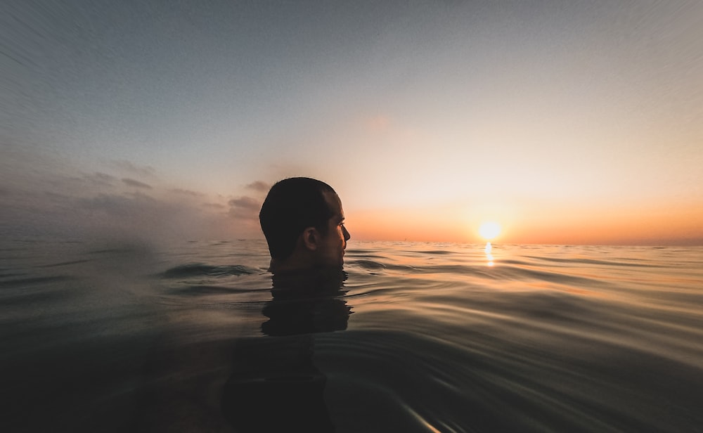 man in water under blue sky during sunset