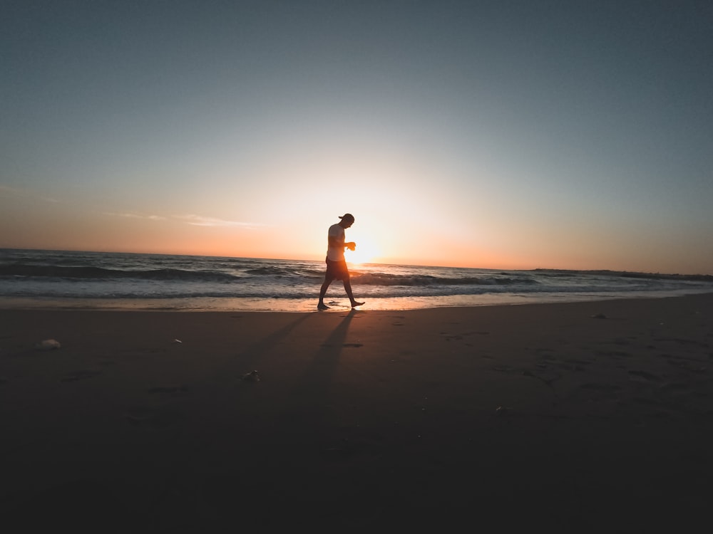 persona que camina por la orilla del mar durante el día