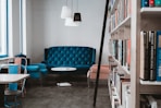 tufted blue 3-seat sofa near white wall and window