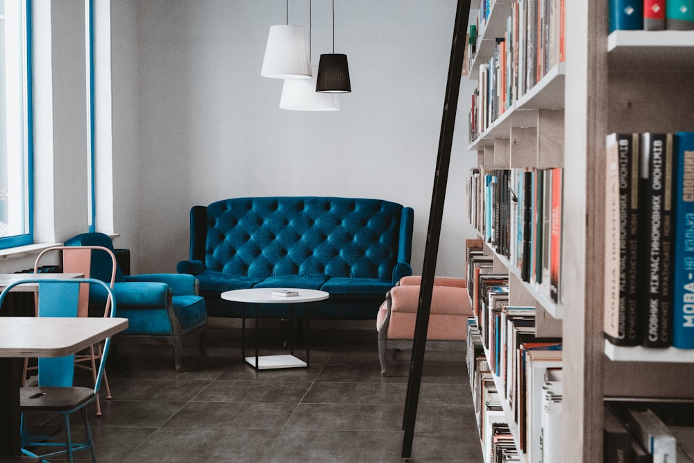 tufted blue 3-seat sofa near white wall and window