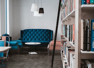 tufted blue 3-seat sofa near white wall and window