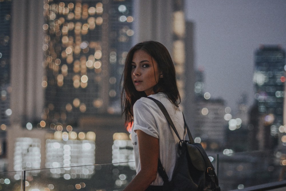 woman in white t-shirt carrying black leather backpack