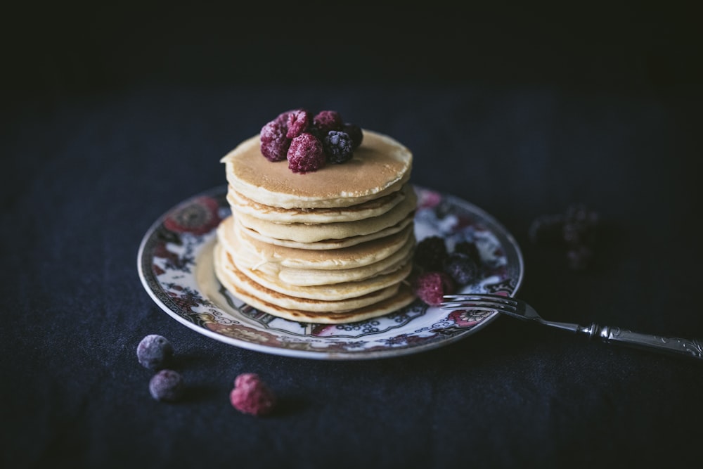 pancakes with raspberry toppings on saucer