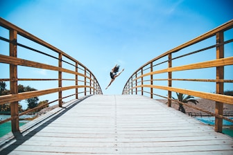 woman jumping near bridge during daytime