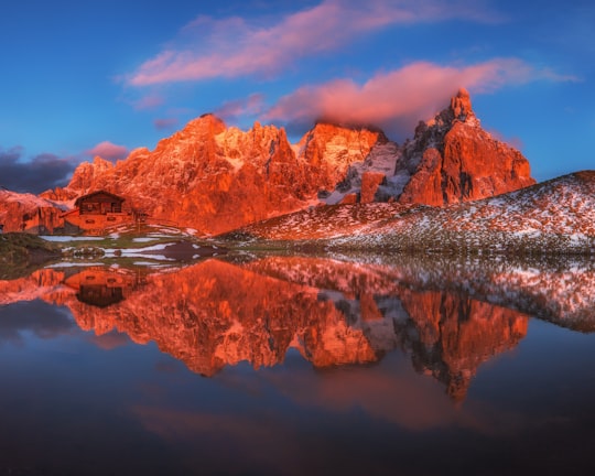 low angle photo of stone hill near bodies of water under blue sky at daytime in Paneveggio Pale di San Martino Italy