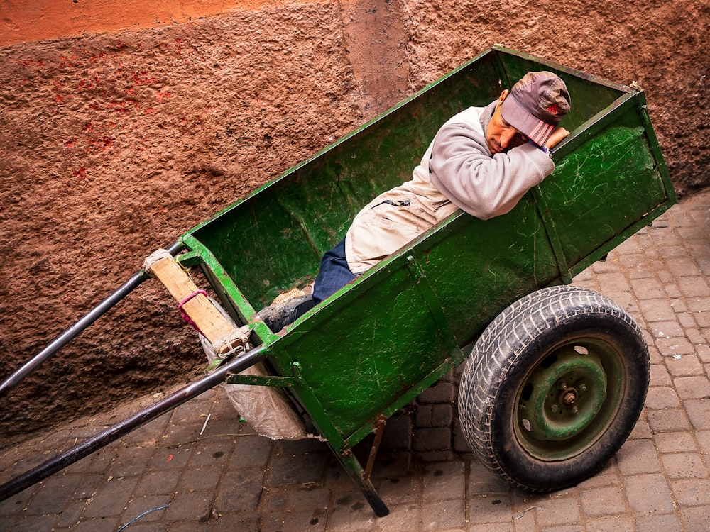 man laying inside green wagon