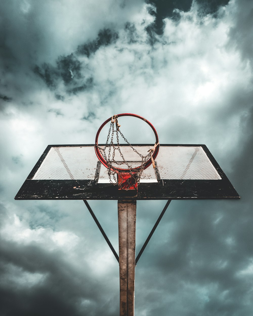 Foto eines tragbaren Basketballkorbs aus weißem und schwarzem Metall unter bewölktem Himmel während des Tages