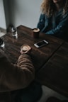 person in brown sweater holding cup while sitting in front of table inside room