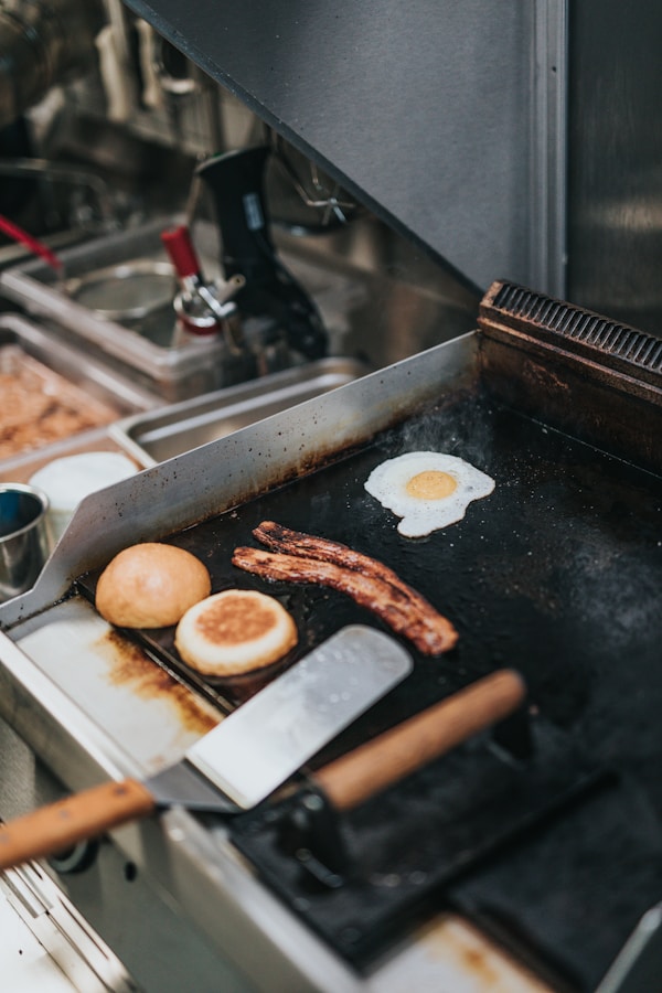 Person cooking bacon, egg, and bread