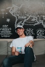 man smiling wearing cap drinking coffee