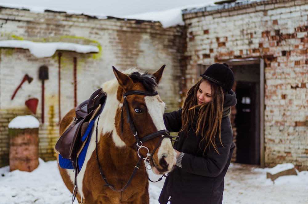 woman holding brown horse's bridle