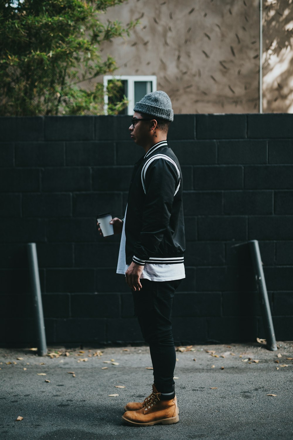 man standing near wall holding a cup looking forward