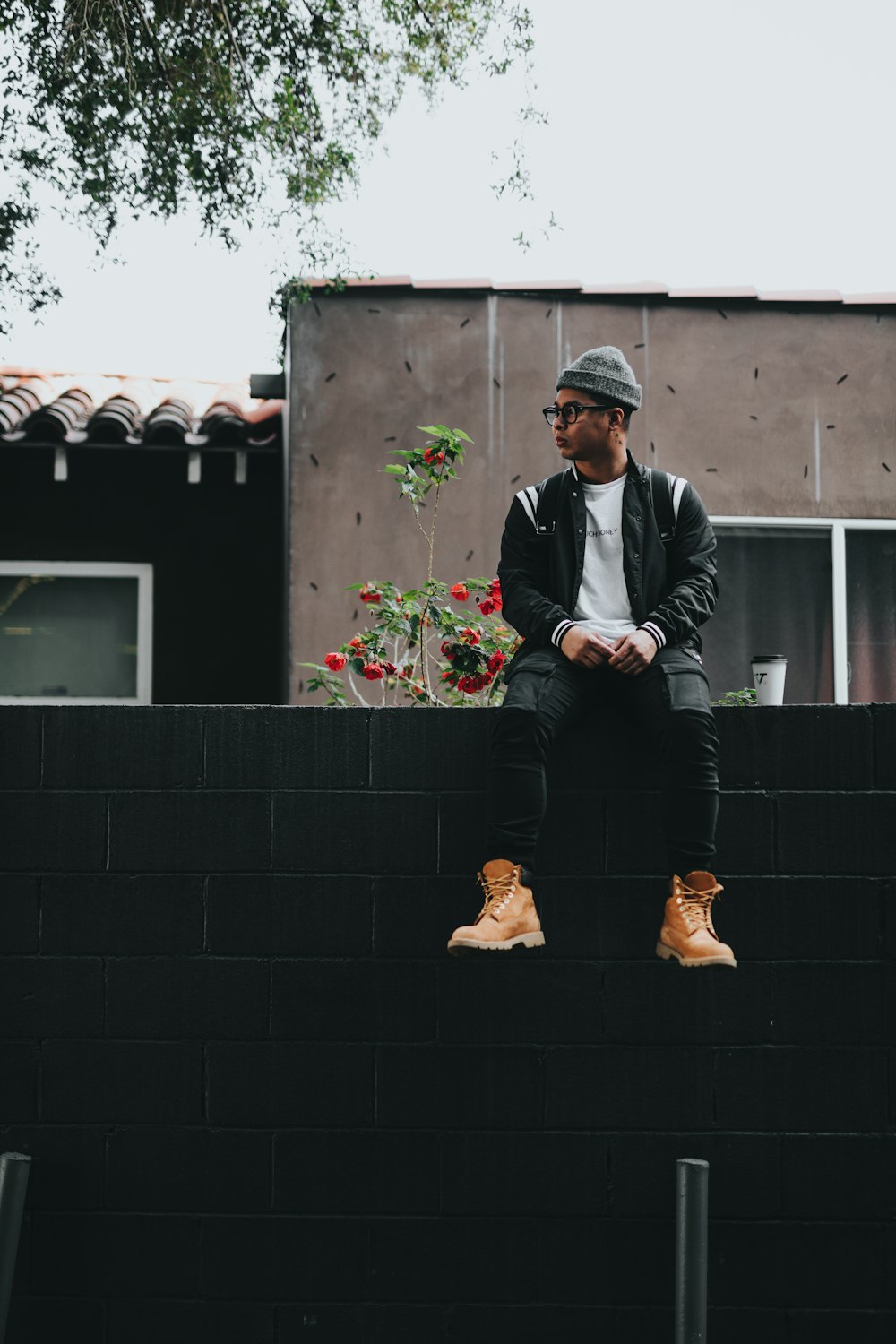 man sitting on black brick fence