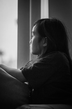 A snapshot capturing the quiet strength of a child sitting alone, looking thoughtfully out a window.