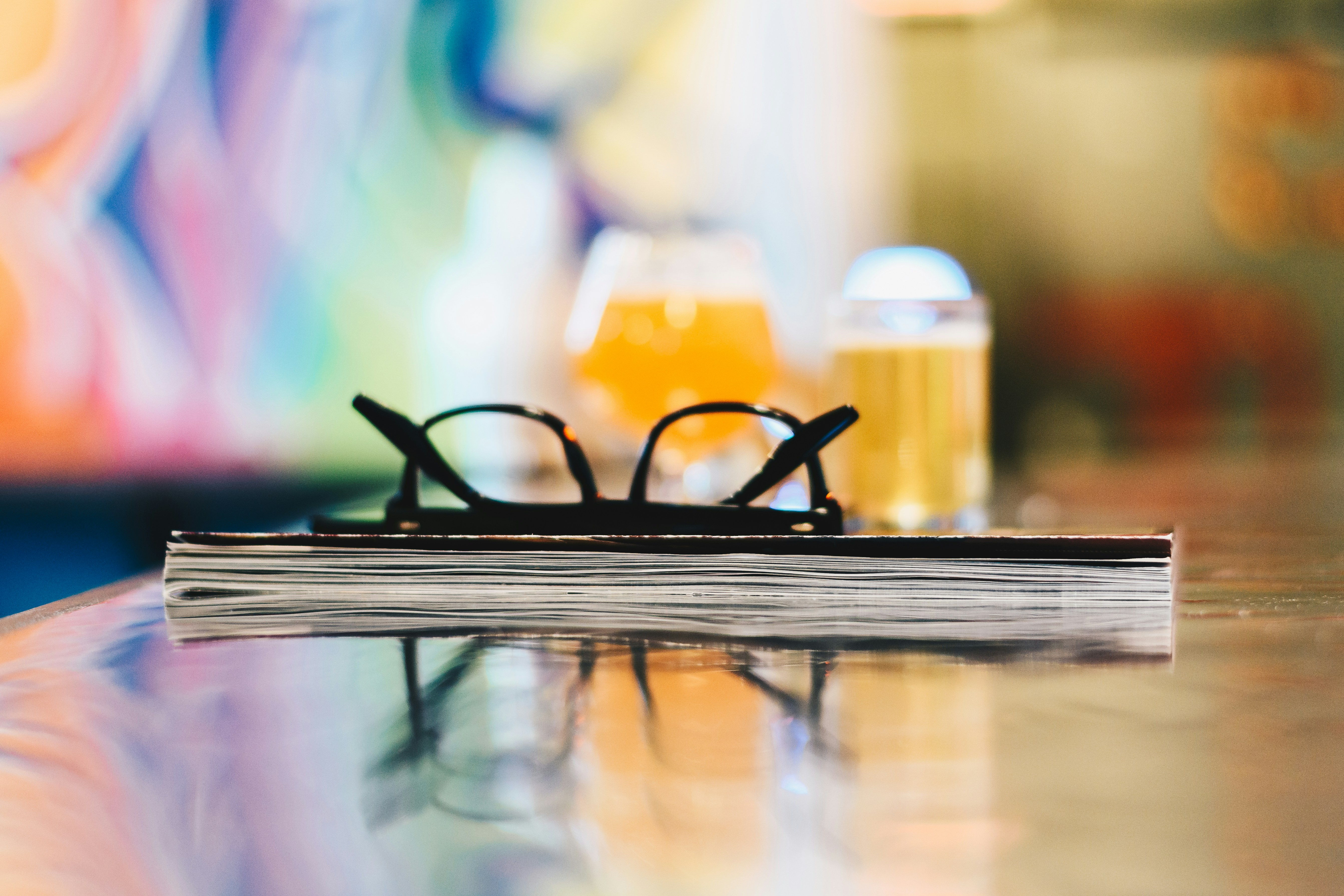 black eyeglasses on closed book on table selective focus photography