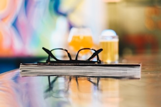 black eyeglasses on closed book on table selective focus photography