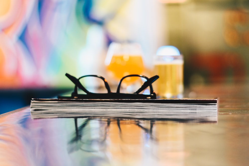 gafas negras en libro cerrado sobre mesa fotografía de enfoque selectivo