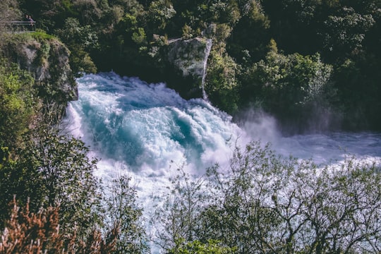 river in forest at daytime in Huka Falls New Zealand
