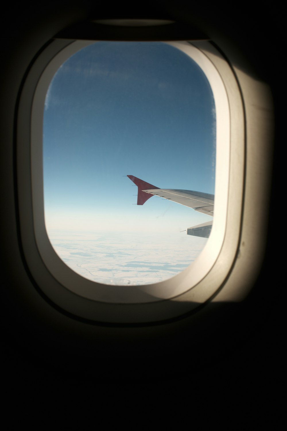 photographie d’extrémité d’aile d’avion à l’intérieur de l’avion au-dessus des nuages pendant la journée