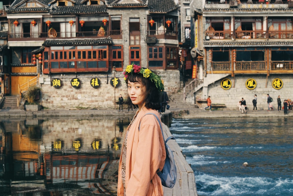 Mujer en vestido rosa de pie frente al lago cerca de los templos