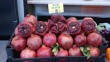 Freshly harvested pomegranates piled in a rustic wooden crate, ready for delivery.