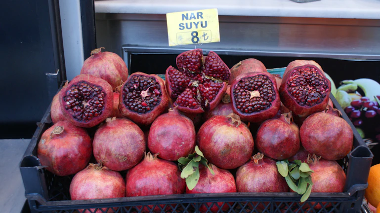 Freshly harvested pomegranates piled in a rustic wooden crate, ready for delivery.