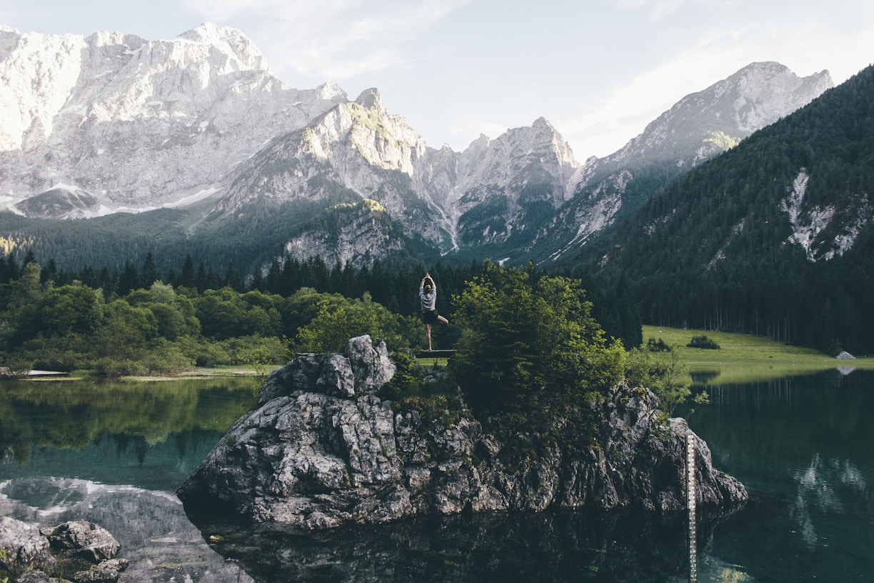 A serene landscape with a person practicing yoga at sunrise.