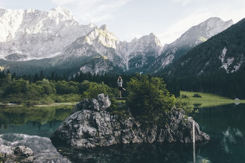 A serene landscape with a person practicing yoga outdoors.