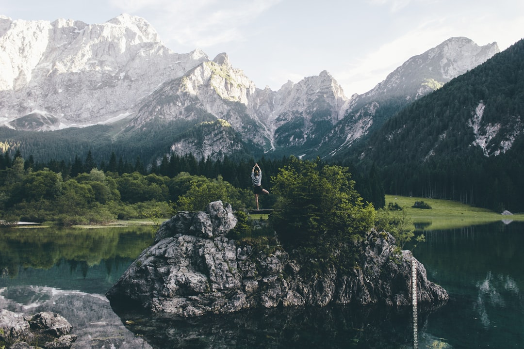 person standing on rock formation surrounded by body of water,