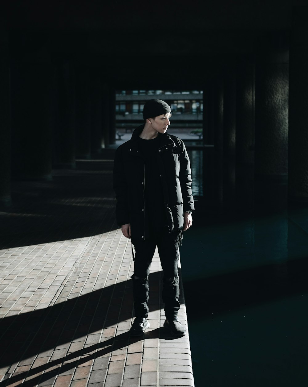 man standing beside gray wall during daytime