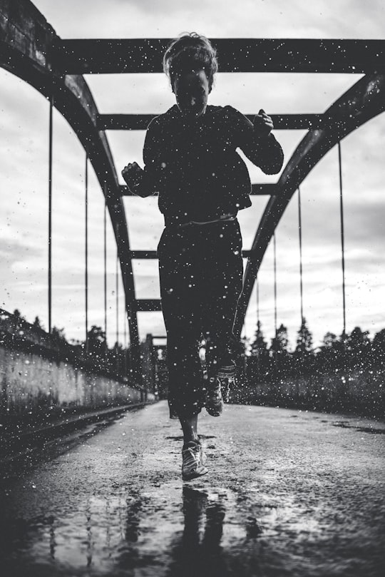 greyscale photography of woman running on bridge in Ljusdal Sweden
