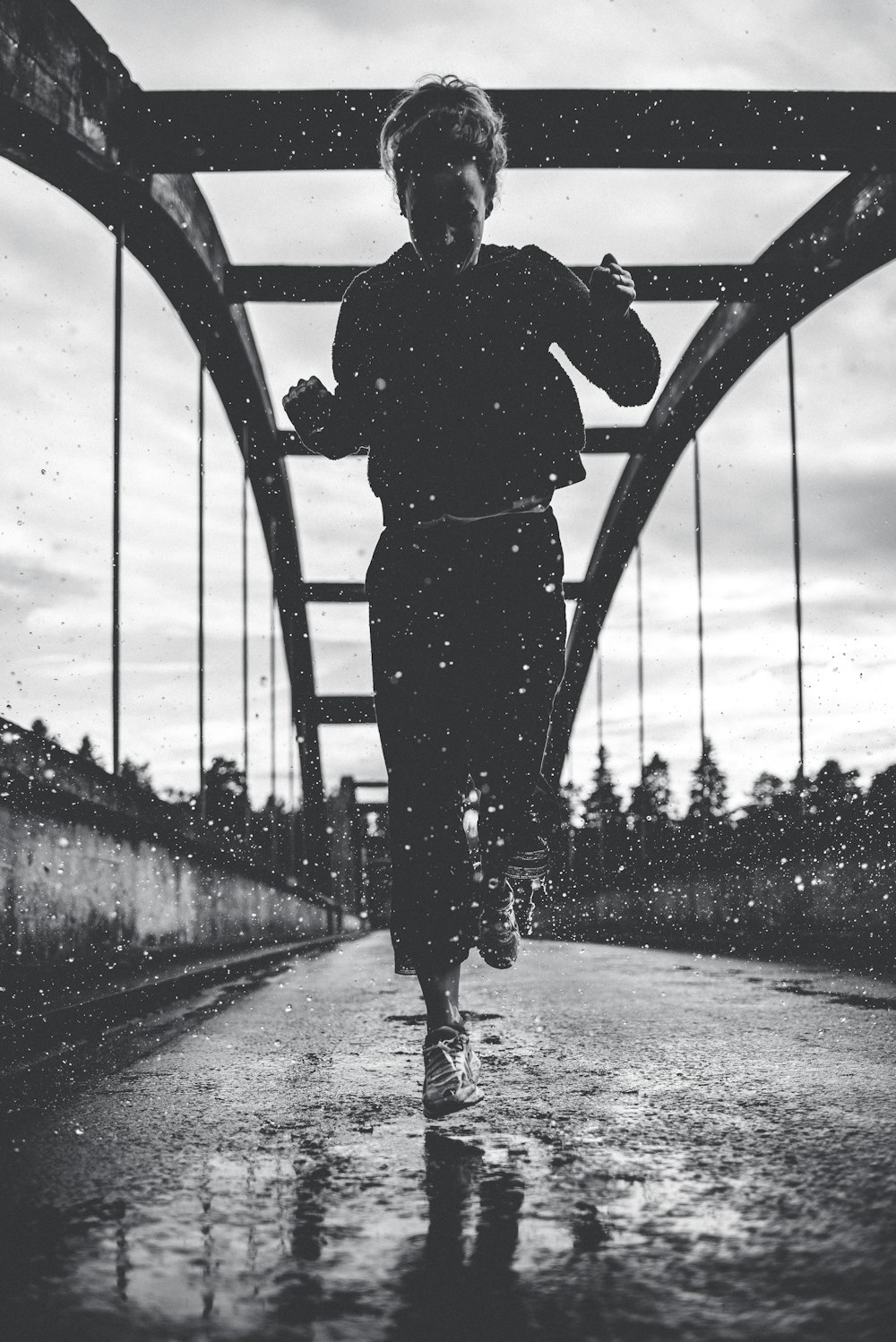 greyscale photography of woman running on bridge